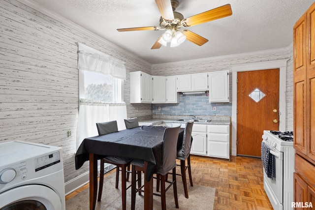 kitchen with sink, light parquet floors, white cabinets, white range with gas cooktop, and washer / clothes dryer