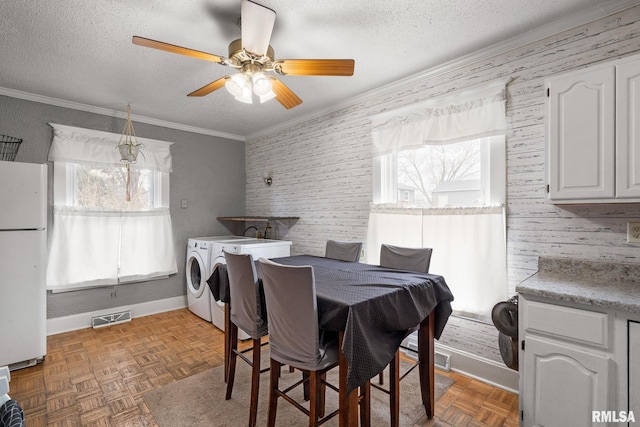 dining space featuring a healthy amount of sunlight, dark parquet flooring, washing machine and dryer, and a textured ceiling