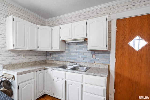 kitchen with white cabinetry, crown molding, sink, and a textured ceiling