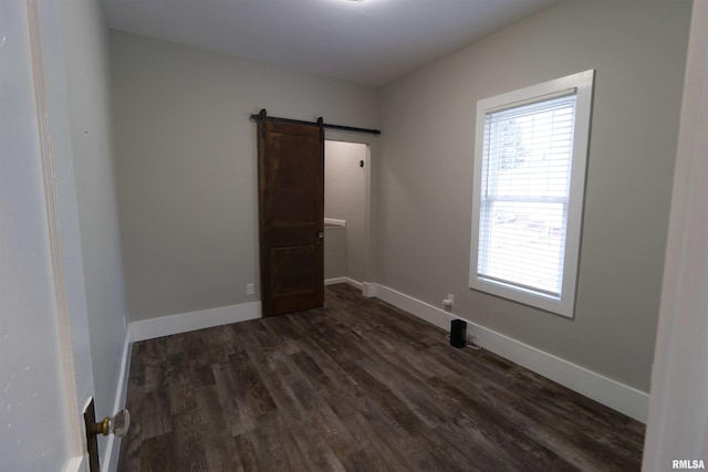 empty room with a barn door and dark hardwood / wood-style floors