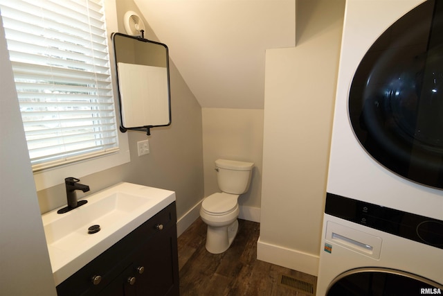 bathroom featuring lofted ceiling, stacked washer / drying machine, toilet, wood-type flooring, and vanity