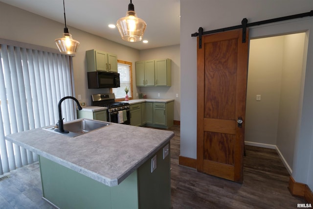 kitchen featuring pendant lighting, sink, a kitchen island with sink, green cabinets, and gas range