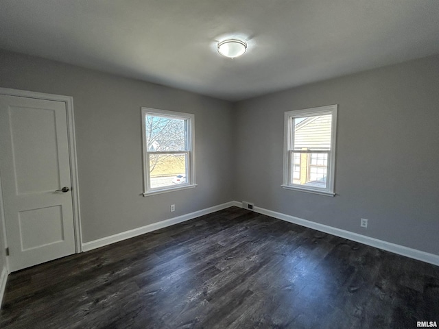 empty room with dark wood-type flooring and plenty of natural light