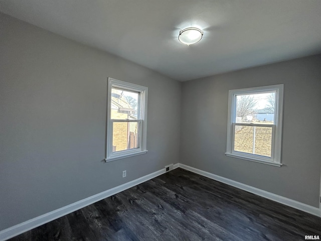 empty room with plenty of natural light and dark hardwood / wood-style floors