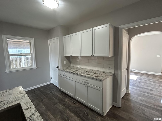 kitchen with backsplash, light stone countertops, dark hardwood / wood-style floors, and white cabinets