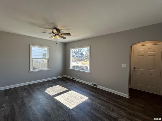 spare room with ceiling fan, a healthy amount of sunlight, and dark hardwood / wood-style flooring