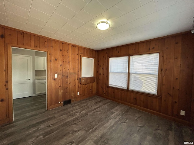 unfurnished room featuring dark hardwood / wood-style floors and wooden walls