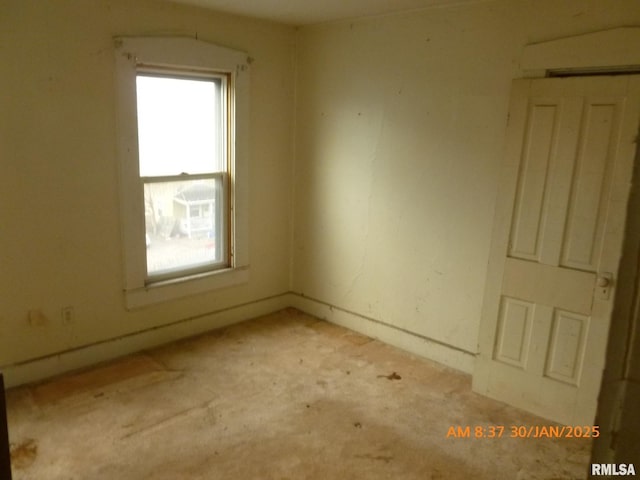 unfurnished room with a wealth of natural light, light colored carpet, and an AC wall unit