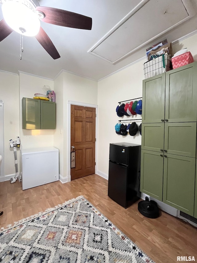 bedroom with black fridge, crown molding, and light hardwood / wood-style flooring