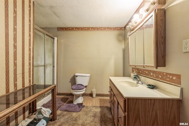 bathroom featuring parquet floors, vanity, toilet, a shower with door, and a textured ceiling