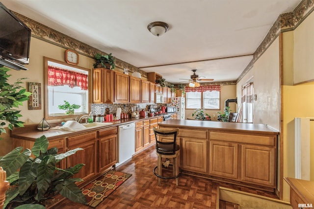 kitchen featuring white appliances, sink, dark parquet floors, and a wealth of natural light