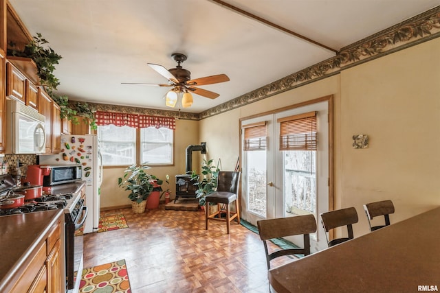 kitchen featuring tasteful backsplash, a wood stove, ceiling fan, light parquet flooring, and gas range oven