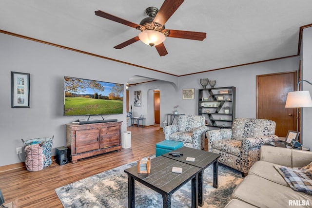 living room with ornamental molding, ceiling fan, and light wood-type flooring