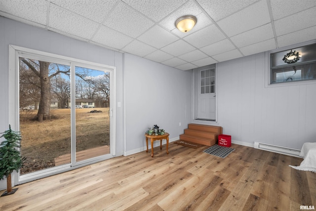 interior space with baseboard heating, hardwood / wood-style floors, and a drop ceiling