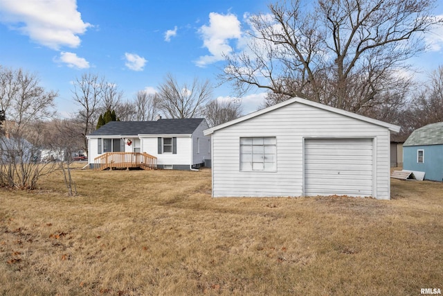 view of front of property featuring a wooden deck, a front yard, and an outbuilding