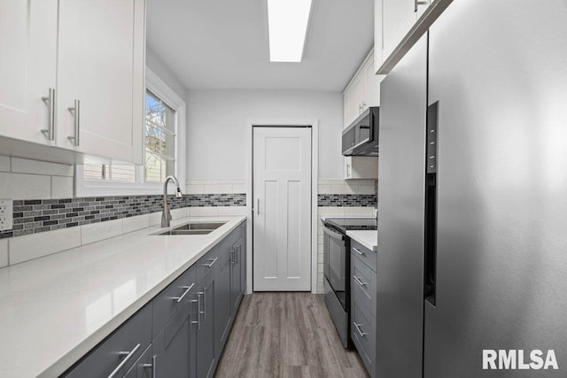 kitchen with stainless steel appliances, white cabinetry, sink, and gray cabinetry