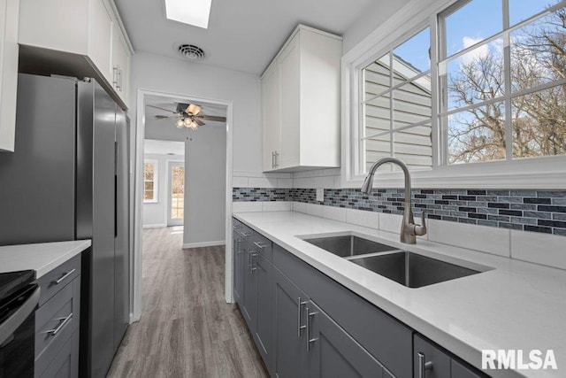 kitchen with gray cabinetry, sink, stainless steel fridge, and white cabinets