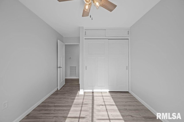 unfurnished bedroom with light hardwood / wood-style flooring, a closet, and ceiling fan