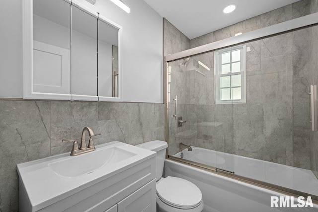 full bathroom with tile walls, vanity, enclosed tub / shower combo, and toilet