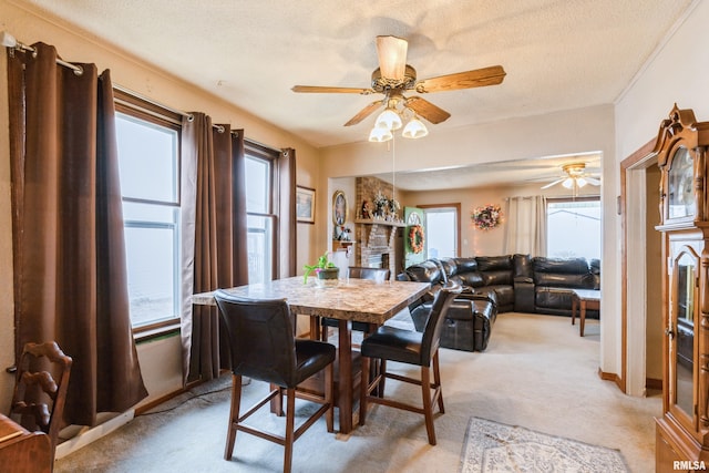 dining room featuring ceiling fan, light carpet, a textured ceiling, and a fireplace