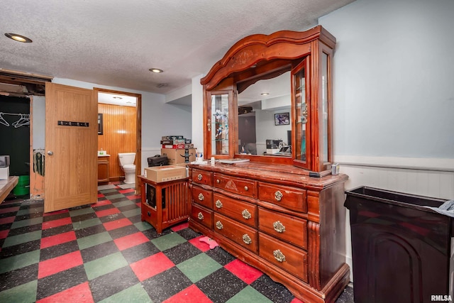 bedroom featuring a walk in closet, ensuite bathroom, and a textured ceiling