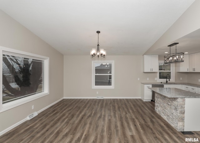 kitchen featuring white cabinetry, light stone counters, decorative light fixtures, a chandelier, and dishwasher