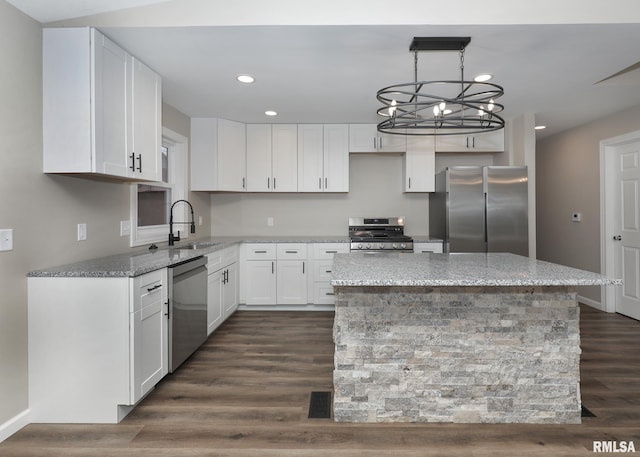 kitchen with sink, appliances with stainless steel finishes, white cabinetry, a center island, and light stone countertops