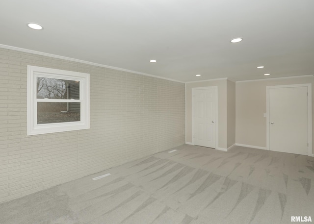 carpeted spare room with ornamental molding and brick wall