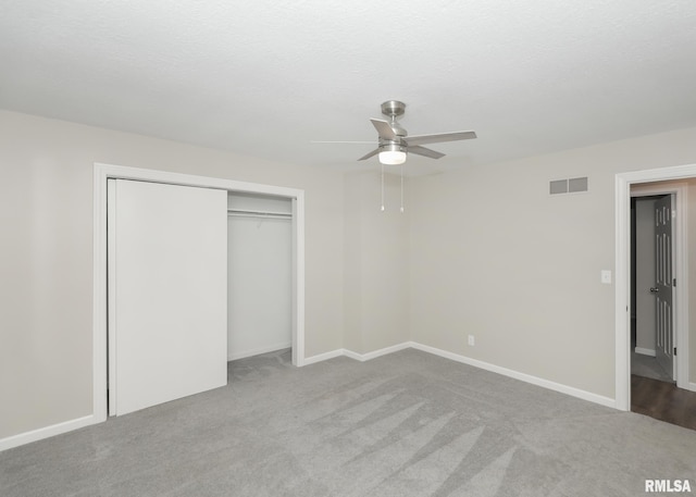 unfurnished bedroom featuring light carpet, a textured ceiling, ceiling fan, and a closet