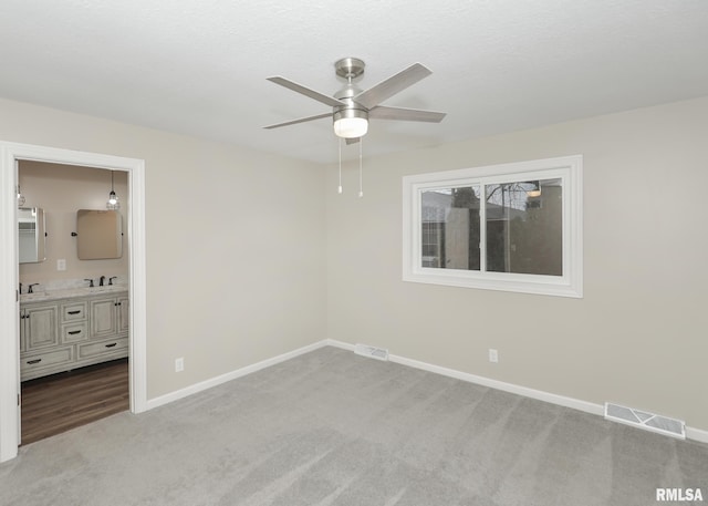 carpeted spare room featuring sink and ceiling fan