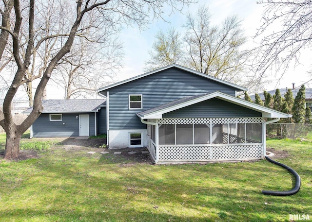 rear view of house featuring a yard and a sunroom