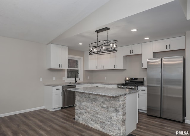 kitchen with white cabinetry, decorative light fixtures, a kitchen island, and appliances with stainless steel finishes