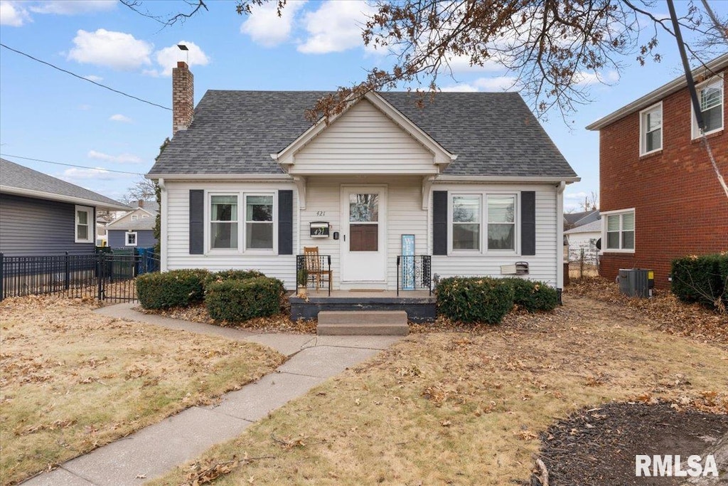 bungalow with central air condition unit, a chimney, fence, and roof with shingles