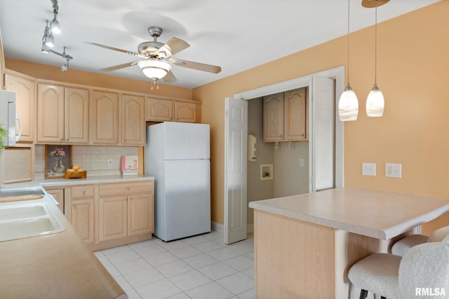 kitchen featuring a breakfast bar, light brown cabinetry, white refrigerator, pendant lighting, and backsplash