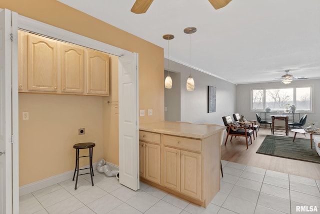 kitchen with light tile patterned flooring, ceiling fan, decorative light fixtures, and light brown cabinets