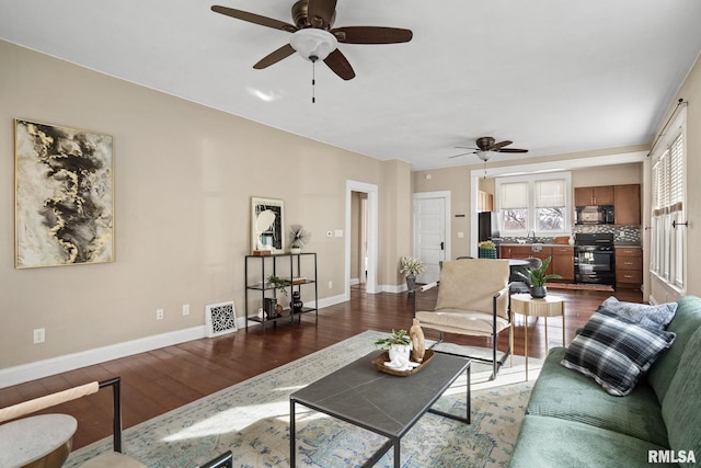 living room featuring ceiling fan, sink, and dark hardwood / wood-style flooring