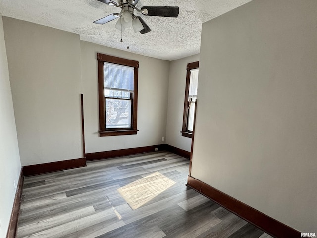 spare room with a ceiling fan, a textured ceiling, baseboards, and wood finished floors