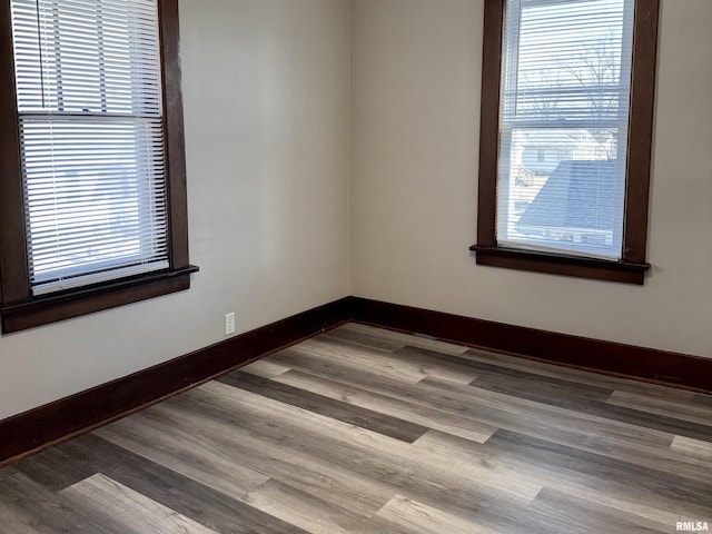 spare room with a healthy amount of sunlight, baseboards, and wood finished floors