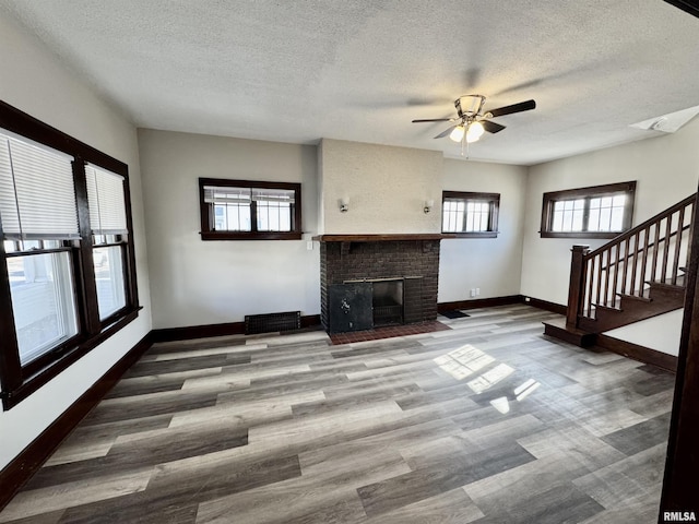 unfurnished living room featuring baseboards, a fireplace, stairway, and wood finished floors