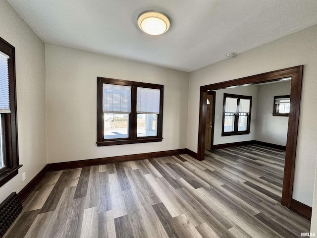 spare room with baseboards and wood finished floors