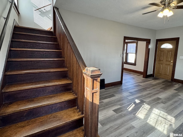 entrance foyer featuring ceiling fan, stairway, wood finished floors, and baseboards