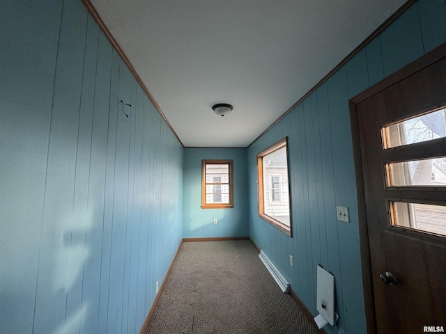 hall with a baseboard heating unit, ornamental molding, and carpet flooring