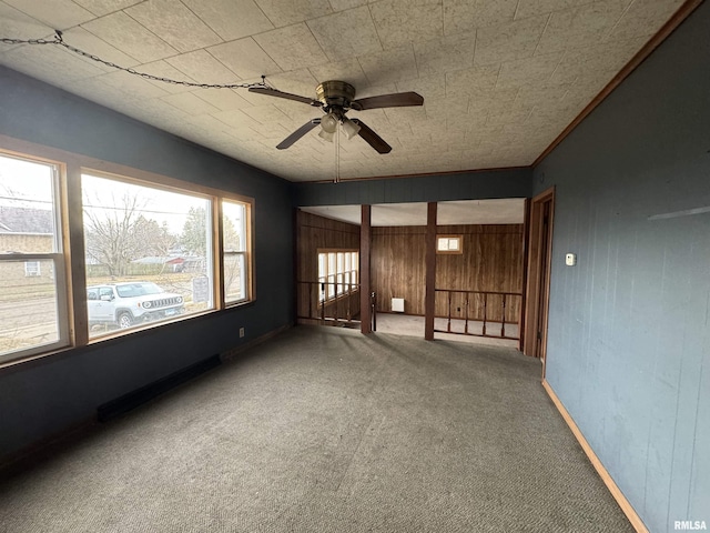 empty room with wood walls, ceiling fan, and carpet