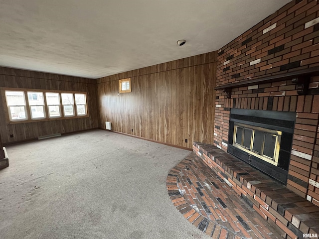 unfurnished living room with carpet, a fireplace, and wood walls