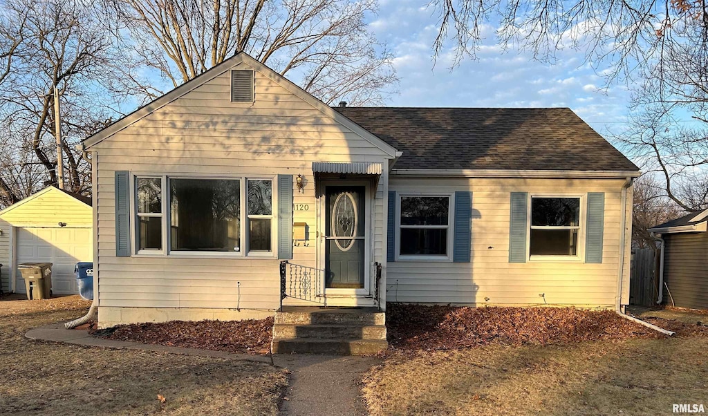 bungalow-style home featuring an outbuilding, roof with shingles, and a detached garage