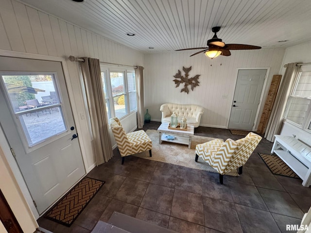 sitting room with ceiling fan, wooden ceiling, and dark tile patterned floors