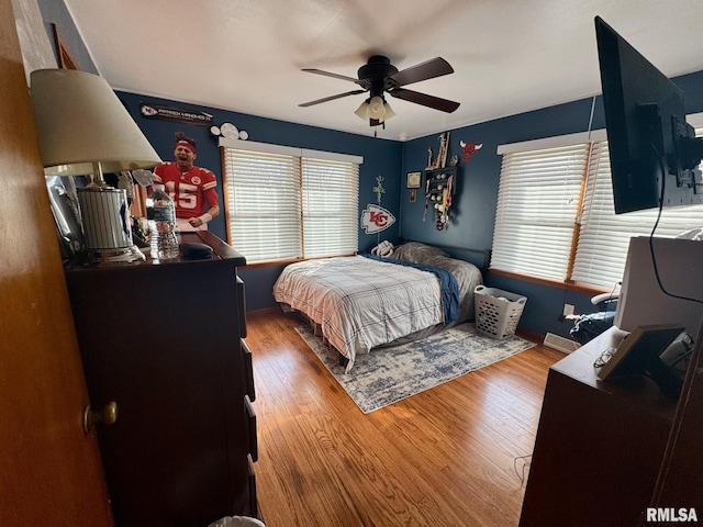 bedroom with multiple windows, hardwood / wood-style floors, and ceiling fan