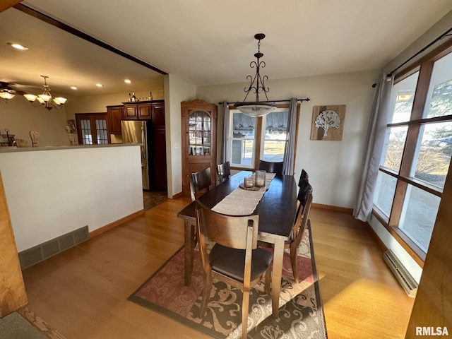 dining area featuring baseboard heating, plenty of natural light, light hardwood / wood-style flooring, and a notable chandelier