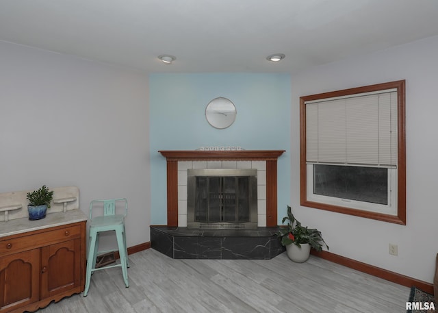 living room featuring a tile fireplace and light hardwood / wood-style floors