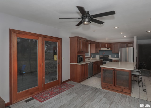 kitchen featuring sink, a breakfast bar area, a center island, stainless steel appliances, and light wood-type flooring